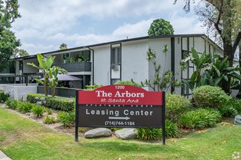 A sign for the arbors at santa ana leasing center in front of a building.